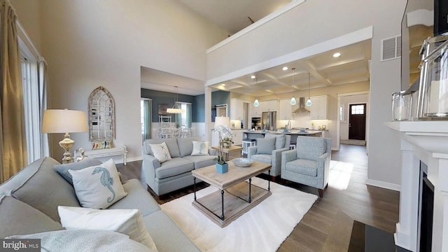 living room featuring dark hardwood / wood-style floors, beam ceiling, coffered ceiling, and a high ceiling