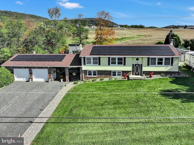 view of front of property with a front yard, a garage, and solar panels