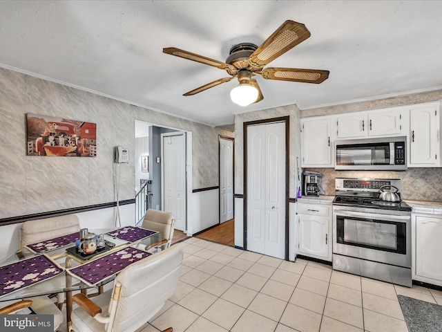 kitchen featuring ceiling fan, crown molding, appliances with stainless steel finishes, and white cabinets