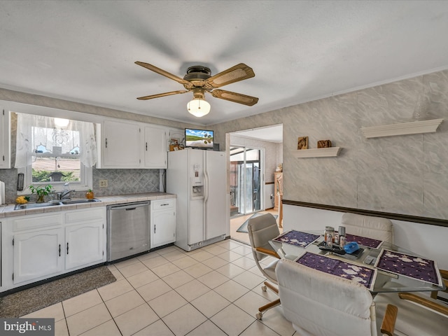 kitchen with tile counters, white cabinetry, stainless steel dishwasher, and white refrigerator with ice dispenser