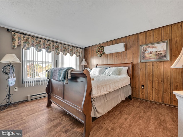 bedroom with baseboard heating, dark wood-type flooring, a wall mounted air conditioner, and wood walls