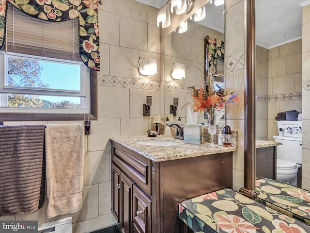 bathroom featuring toilet, vanity, and tile walls