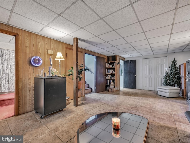 living room featuring a paneled ceiling and wooden walls