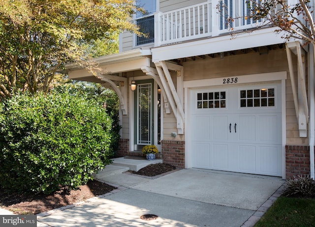 view of exterior entry with a balcony and a garage