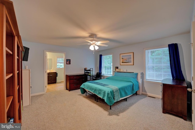 carpeted bedroom with ensuite bathroom and ceiling fan