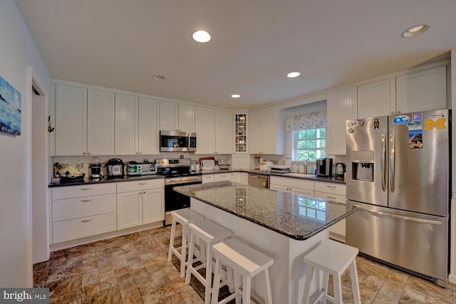 kitchen with a kitchen island, a breakfast bar area, stainless steel appliances, and white cabinets