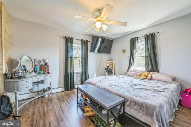 bedroom featuring dark hardwood / wood-style flooring, multiple windows, baseboard heating, and ceiling fan