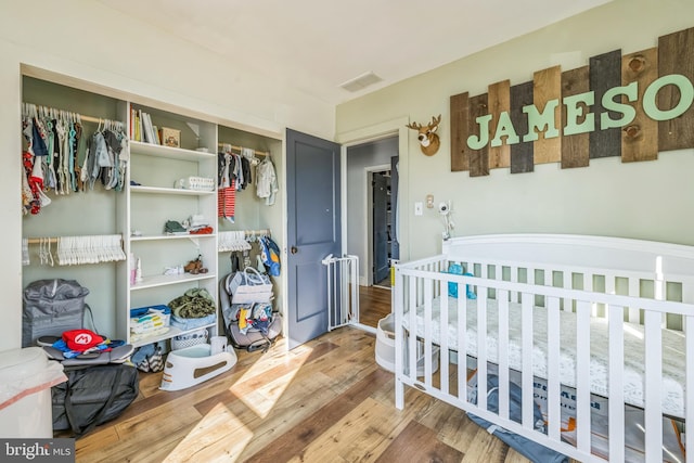 bedroom featuring a closet, a nursery area, and hardwood / wood-style flooring