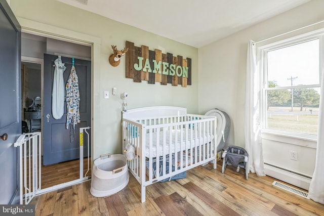 bedroom featuring a closet, a nursery area, and hardwood / wood-style flooring