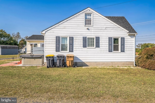 rear view of house featuring a hot tub and a lawn