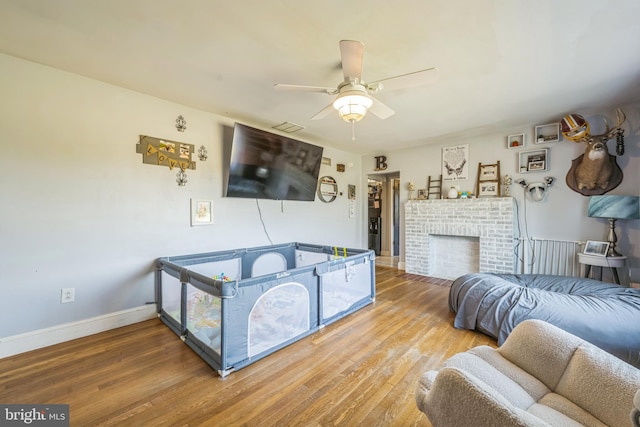 living room with a fireplace, wood-type flooring, and ceiling fan