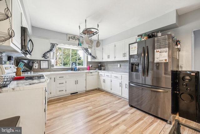 kitchen with sink, light wood-type flooring, backsplash, white cabinetry, and stainless steel appliances