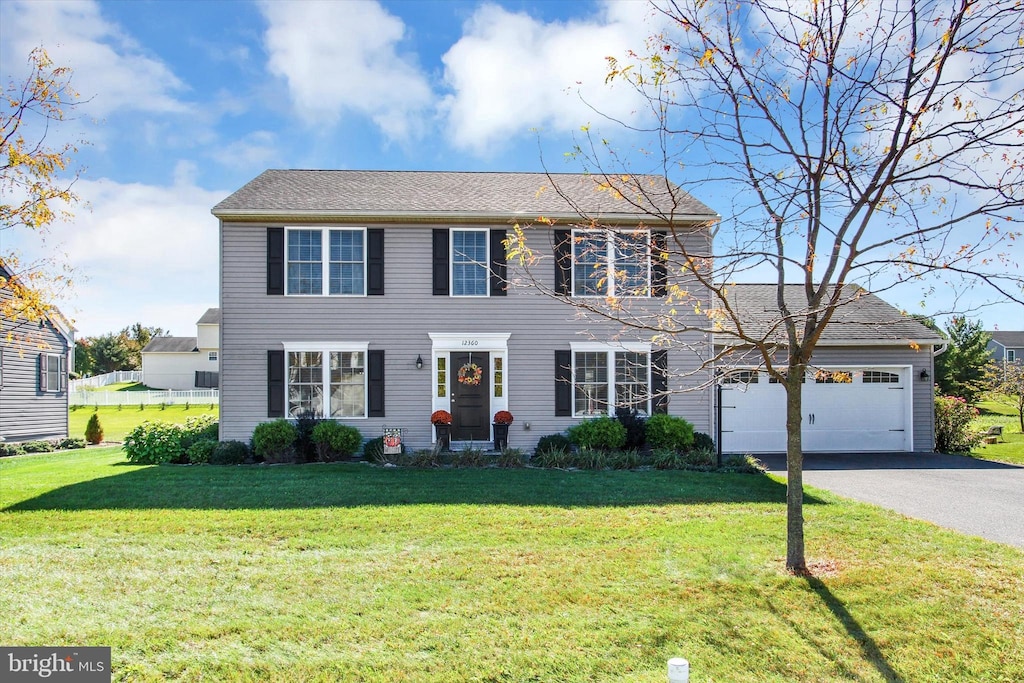 colonial inspired home with a front yard and a garage