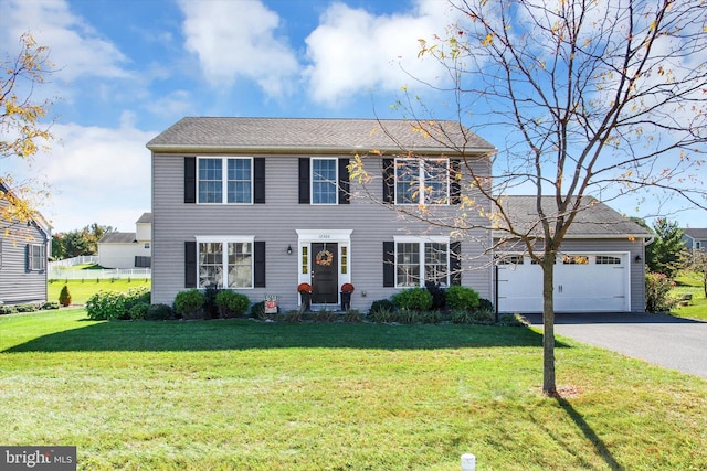 colonial inspired home with a front yard and a garage