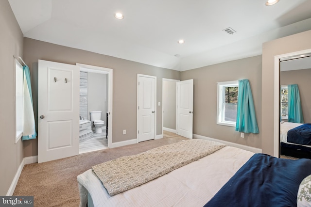 bedroom featuring connected bathroom and light carpet