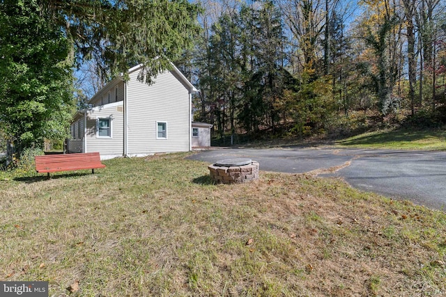 view of side of property with an outdoor fire pit, a yard, and a wooden deck