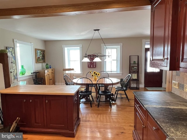 kitchen featuring decorative backsplash, pendant lighting, light wood-type flooring, and beam ceiling