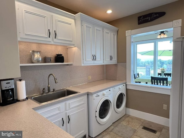 clothes washing area with cabinets, washing machine and dryer, and sink