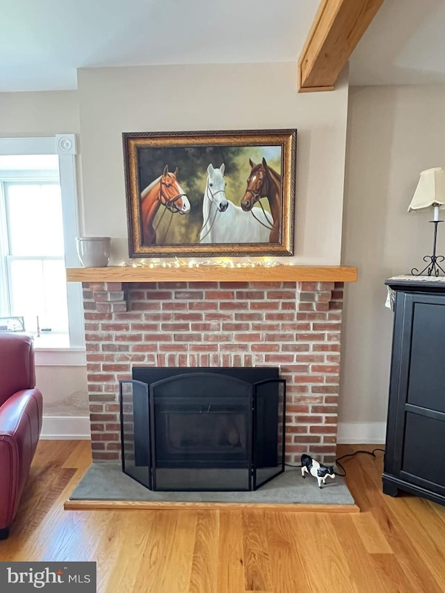 room details featuring beamed ceiling, hardwood / wood-style floors, and a fireplace