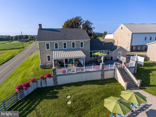 rear view of house featuring a lawn, cooling unit, and a patio