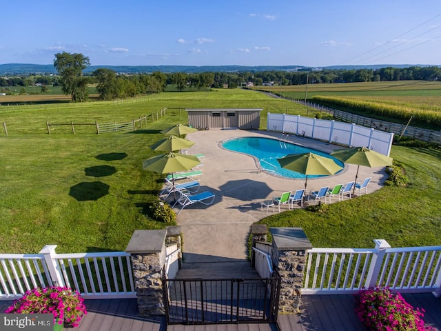 view of pool with a patio area and a rural view