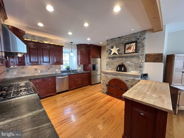 kitchen with appliances with stainless steel finishes, light wood-type flooring, decorative light fixtures, and sink