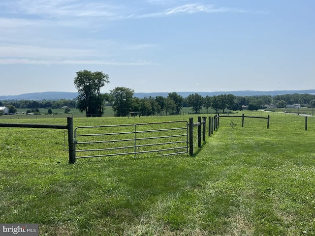 view of gate with a yard and a rural view