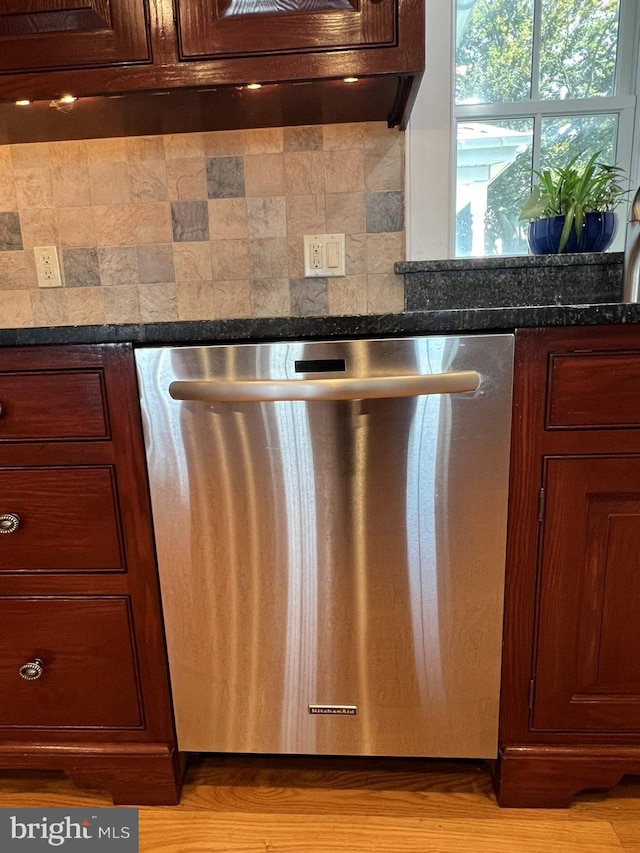 details featuring light wood-type flooring, tasteful backsplash, stainless steel dishwasher, and dark stone counters