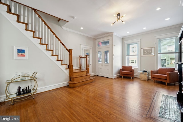 entrance foyer with ornamental molding, an inviting chandelier, and hardwood / wood-style floors