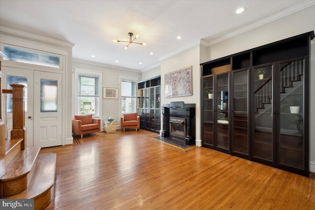 unfurnished living room with wood-type flooring, a fireplace, a chandelier, and ornamental molding