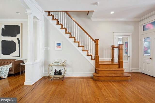 entryway featuring ornamental molding, light wood-type flooring, and decorative columns