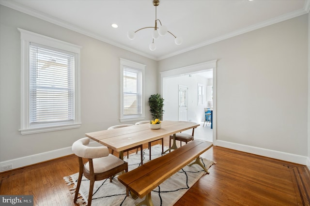 dining space featuring ornamental molding, hardwood / wood-style flooring, a healthy amount of sunlight, and a notable chandelier