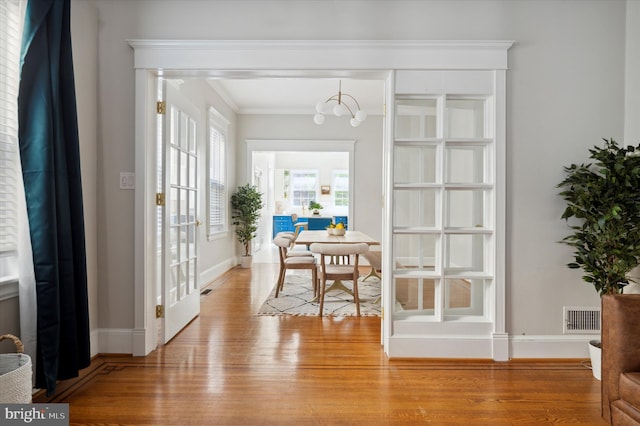 interior space with ornamental molding, an inviting chandelier, and light wood-type flooring