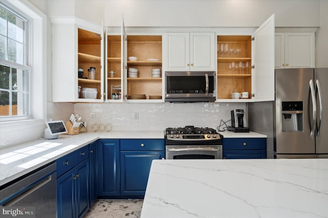 kitchen featuring appliances with stainless steel finishes, light stone counters, white cabinetry, and blue cabinetry