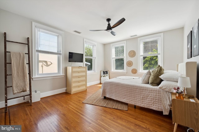 bedroom with ceiling fan, hardwood / wood-style floors, and multiple windows