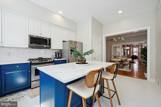 kitchen with a kitchen island, blue cabinetry, appliances with stainless steel finishes, a kitchen breakfast bar, and light wood-type flooring