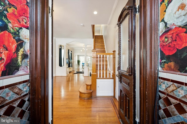 corridor featuring ornamental molding, light hardwood / wood-style flooring, and tile walls