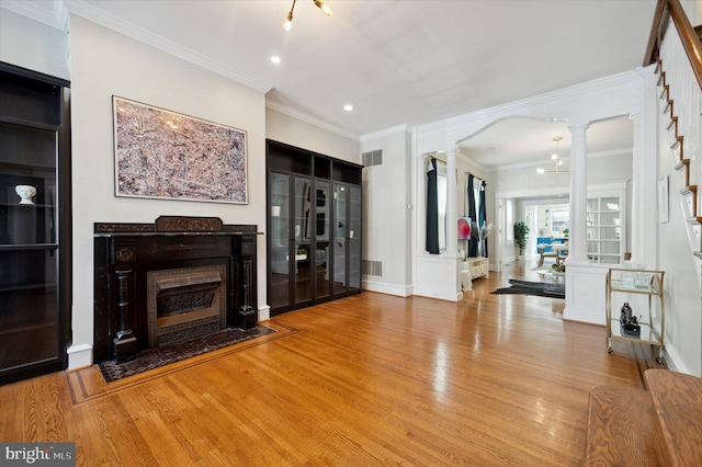 living room featuring ornate columns, ornamental molding, and light wood-type flooring