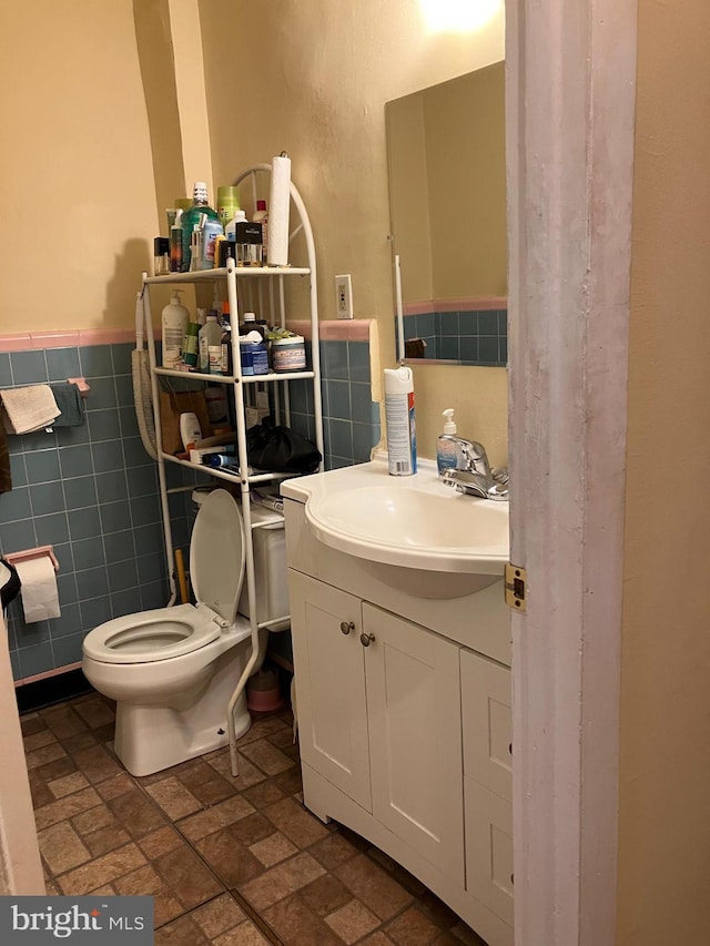 bathroom featuring vanity, toilet, and tile walls