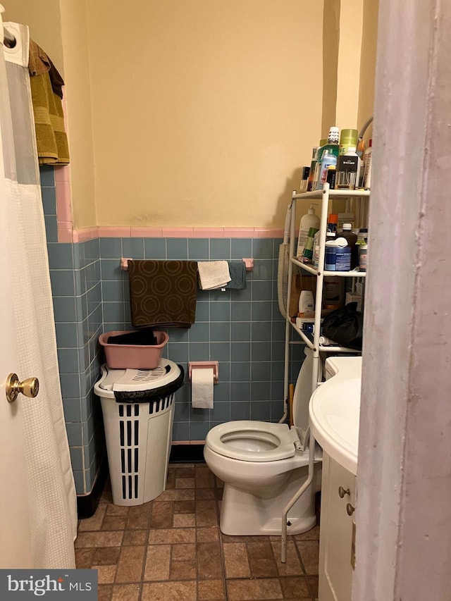 bathroom featuring toilet and tile walls