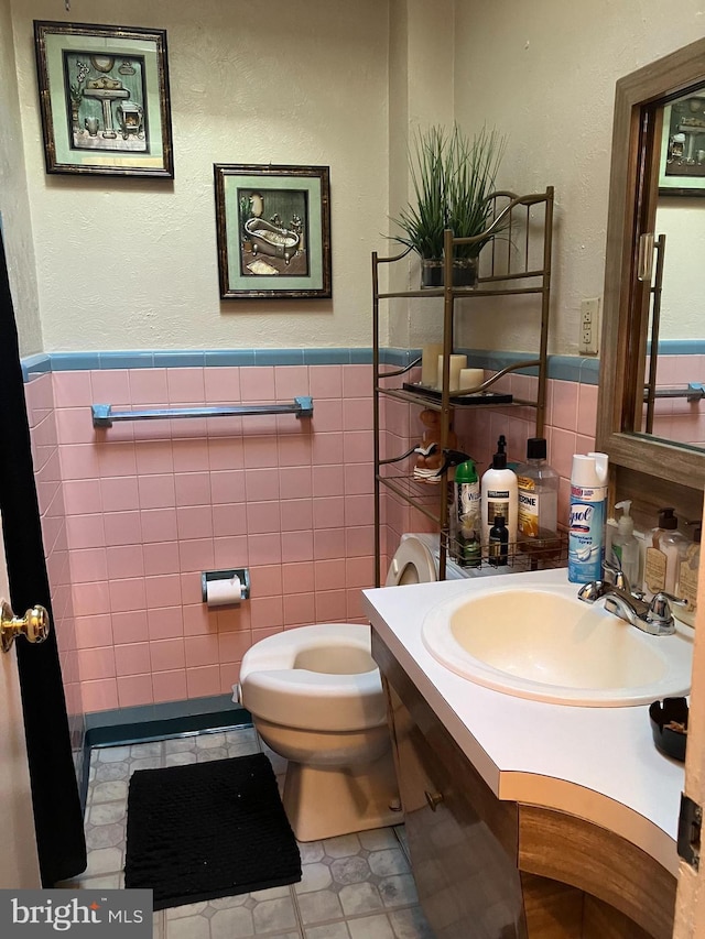 bathroom featuring sink, tile walls, and toilet