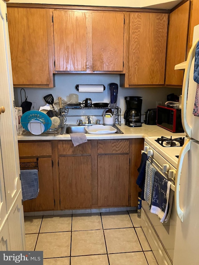 kitchen with sink, white appliances, and light tile patterned flooring