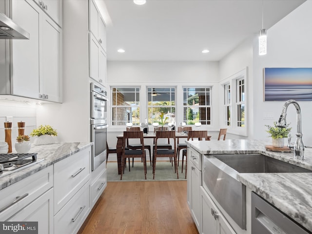 kitchen with pendant lighting, white cabinets, and wood-type flooring