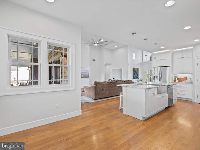 kitchen featuring hanging light fixtures, a center island with sink, sink, white cabinetry, and appliances with stainless steel finishes