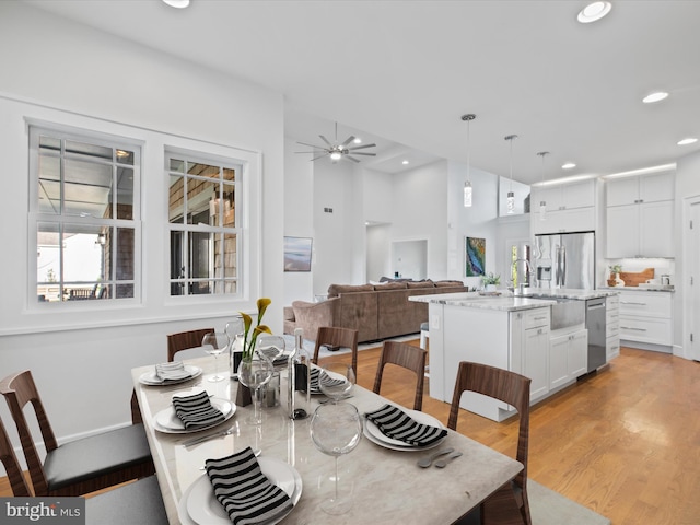 dining space with light hardwood / wood-style flooring, sink, and ceiling fan