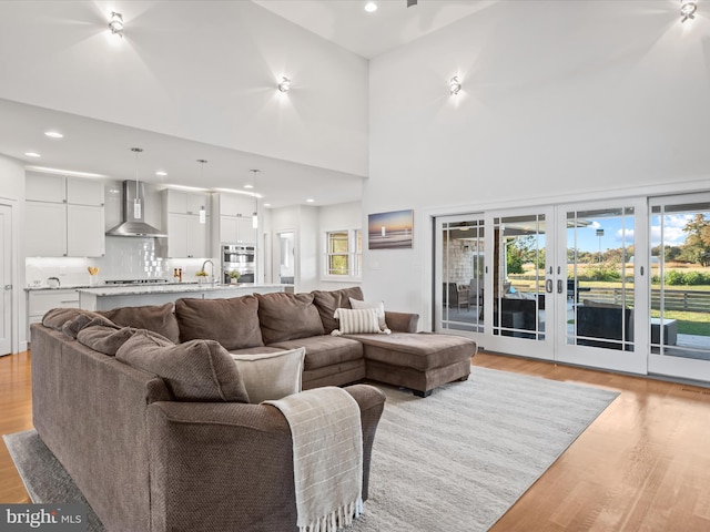 living room with sink, french doors, light hardwood / wood-style floors, and a towering ceiling