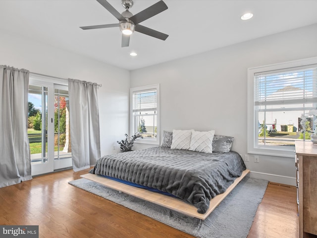 bedroom featuring access to exterior, ceiling fan, multiple windows, and hardwood / wood-style flooring