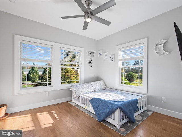 bedroom featuring hardwood / wood-style floors, multiple windows, and ceiling fan