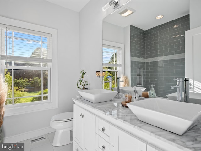 bathroom featuring toilet, vanity, and plenty of natural light