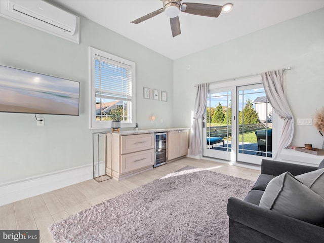 living room featuring a wall unit AC, bar, light hardwood / wood-style flooring, beverage cooler, and ceiling fan